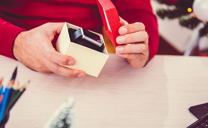 A man is opening a gift box that has a smartwatch inside.