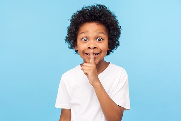 A little boy making silence gesture with finger on his lips.