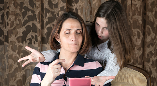 Mother and daughter in living room. The daughter seems unhappy about what is on the computer.