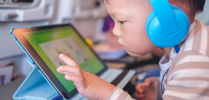 Jeune enfant avec casque d'écoute jouant avec un jouet électronique connecté à Internet.
